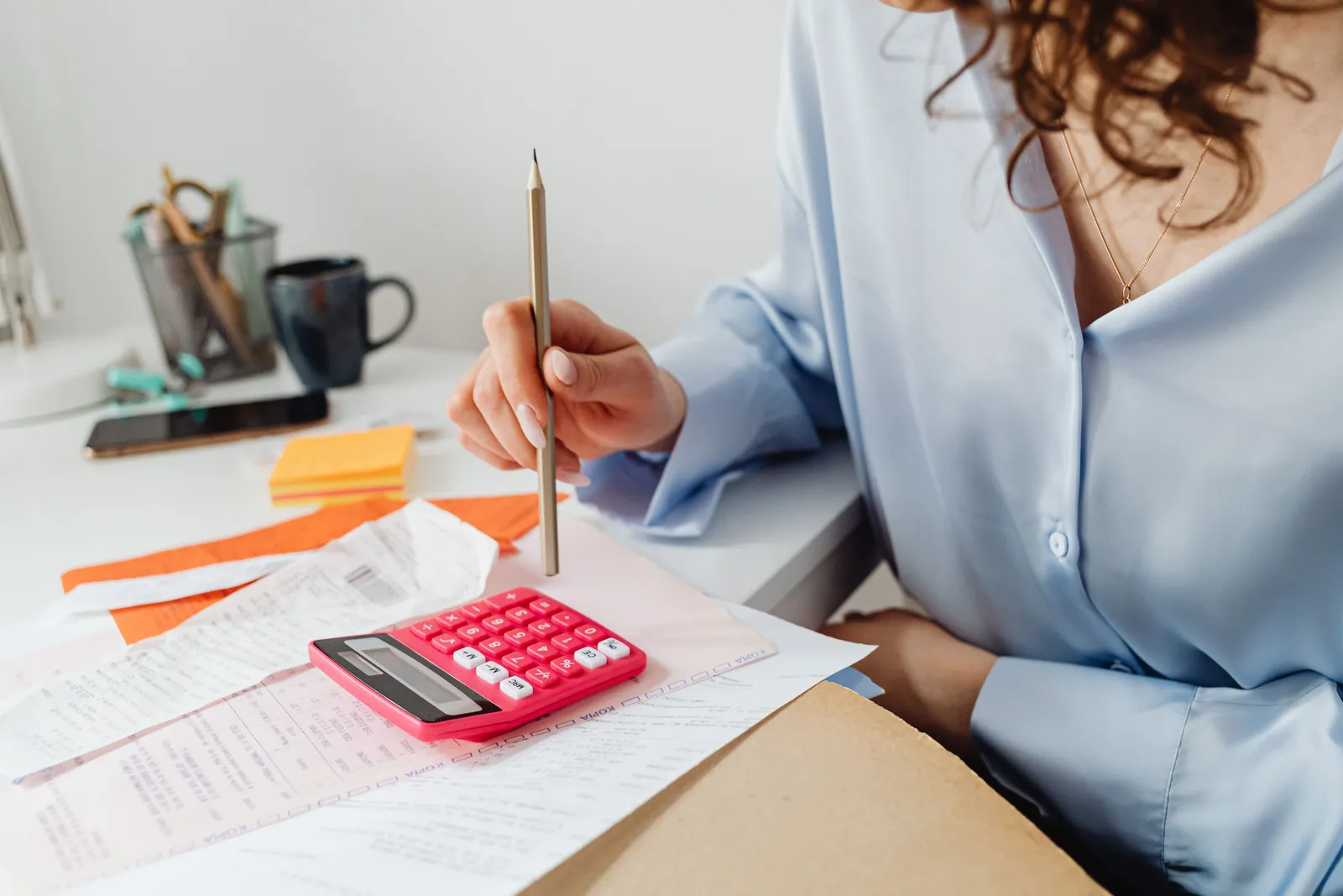 Income documents for an FHA loan Woman reviewing printed financial paperwork with a pink calculator, like the income documents an FHA lender checks