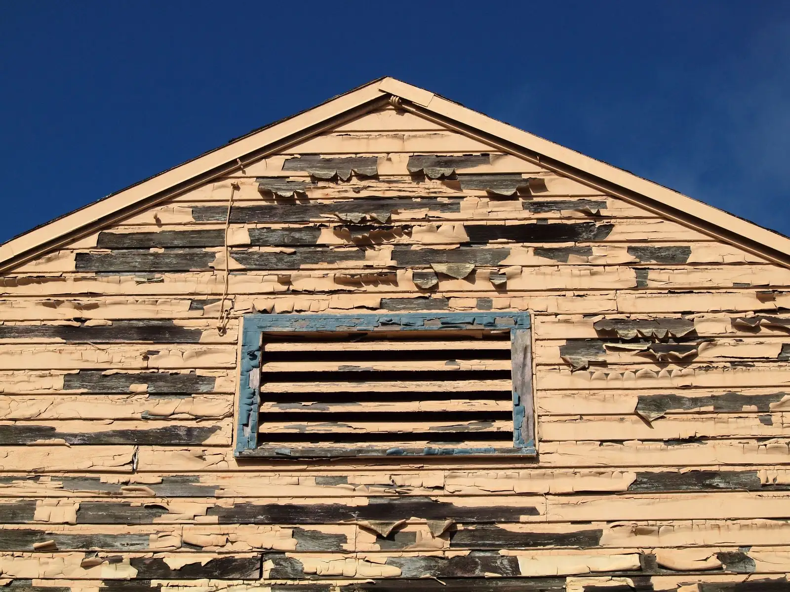 Peeling paint on the wooden siding of an older house, a common FHA appraisal repair item