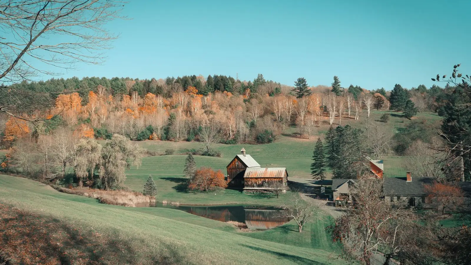 USDA home loans and rural New England homes New England farmhouse and barn in a green valley with autumn trees, the kind of rural setting USDA home loans serve