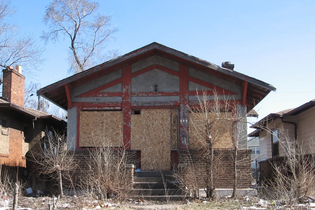 A vacant house with boarded-up windows needing repairs, for a guide to buying a foreclosure with a VA loan