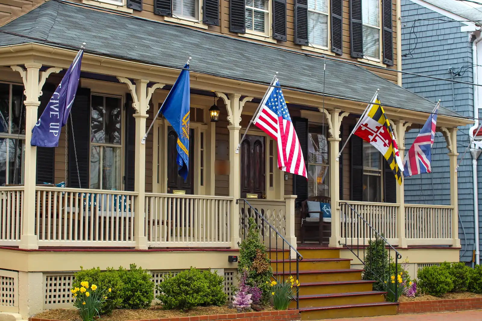 Historic Annapolis house with a wide front porch flying American, Maryland, and other flags along the rail