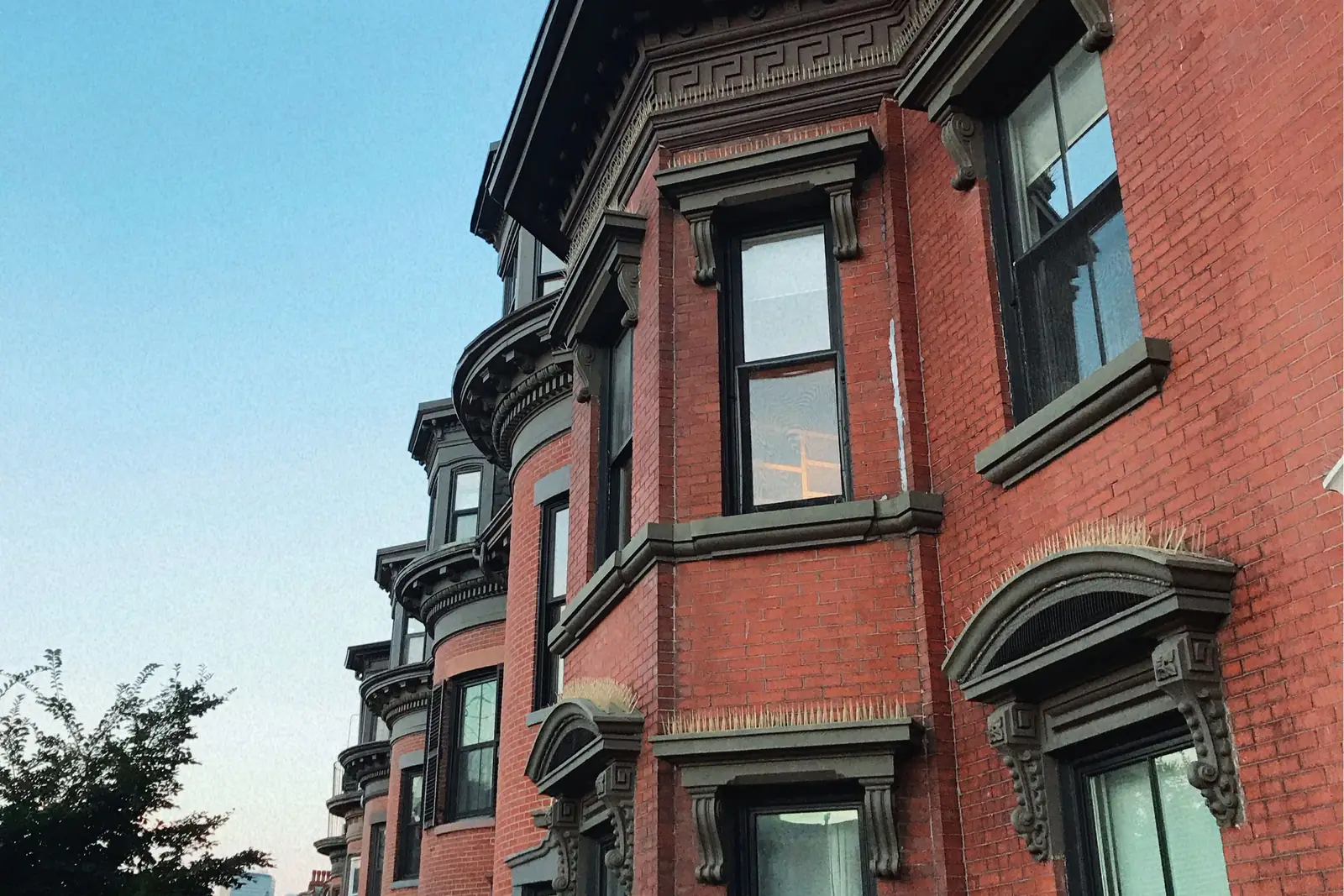 Row of red brick bowfront rowhouses in Boston, the kind of older multifamily buildings investors buy