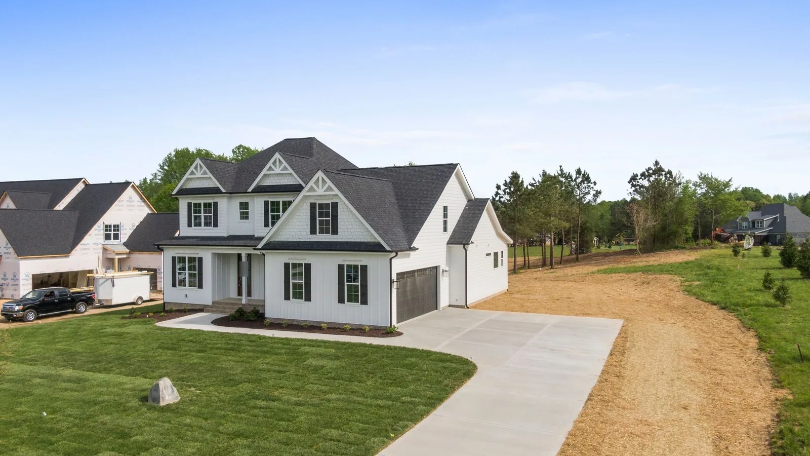 Newly built white farmhouse style home with a fresh lawn and new driveway