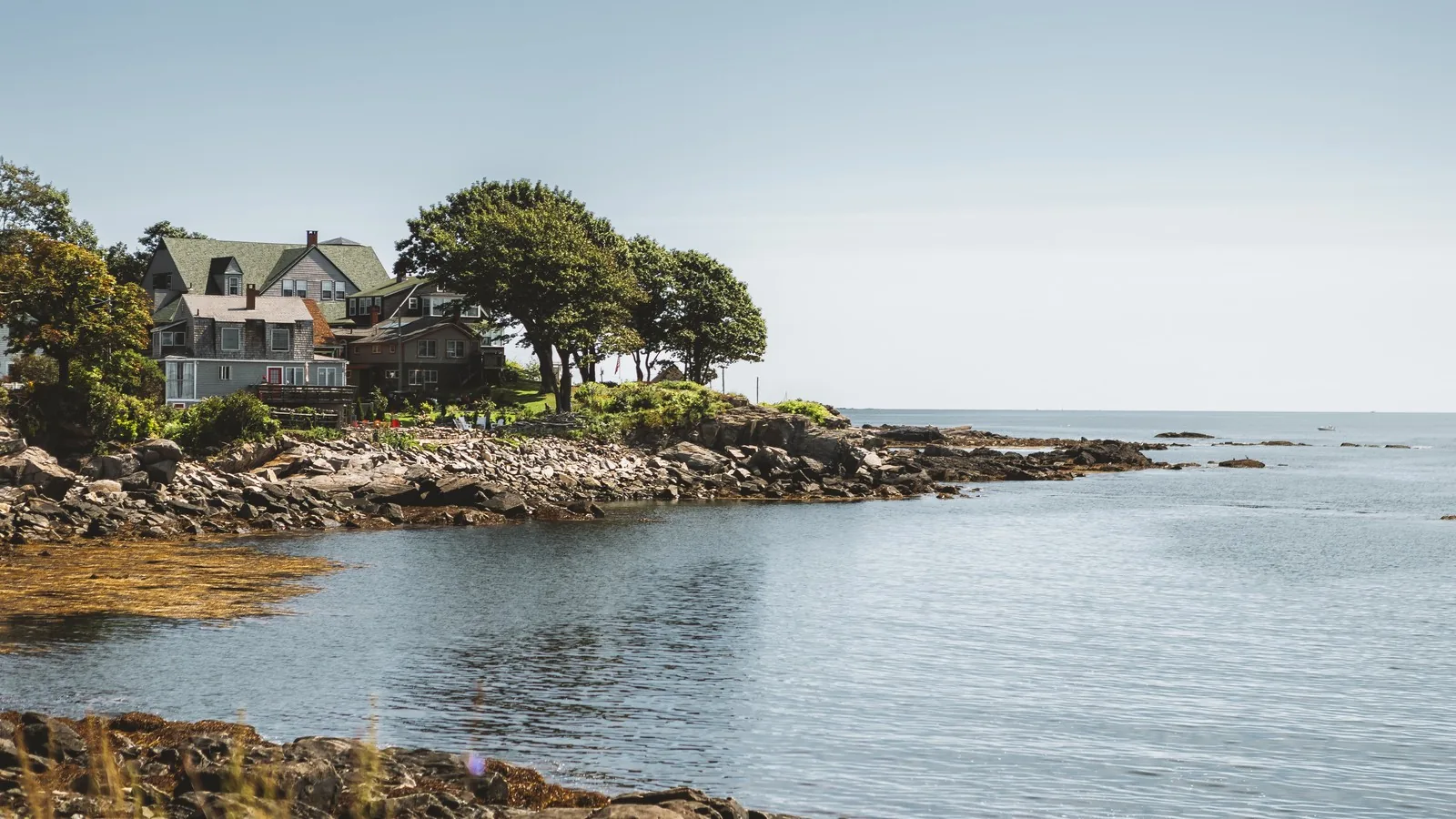 Older shingle and clapboard houses among trees on the rocky Casco Bay shore in Portland, Maine, for a guide to why buyers choose FHA loans in Portland, ME