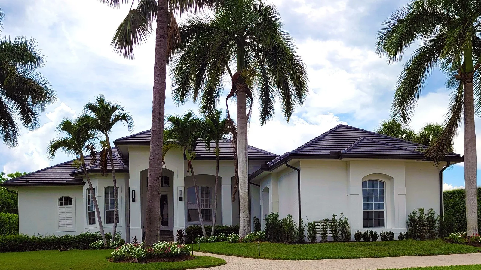 Single story white stucco home with palm trees and a tile roof