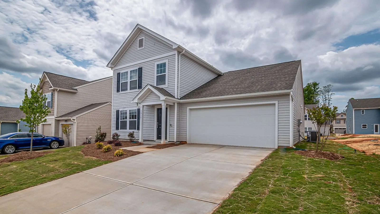 Gray two story house with an attached garage and new lawn