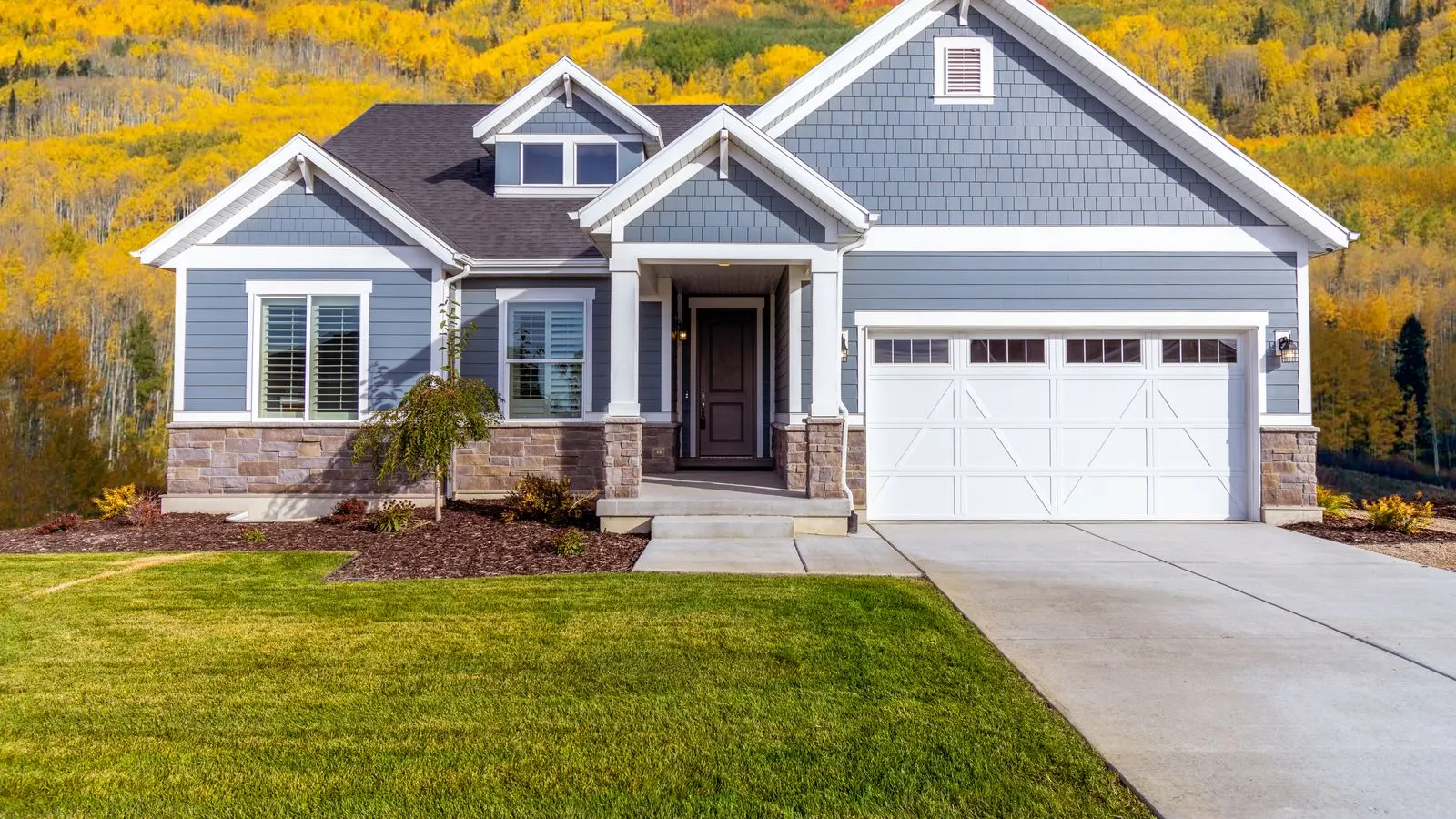 Blue gray family home with fall color on the hills behind