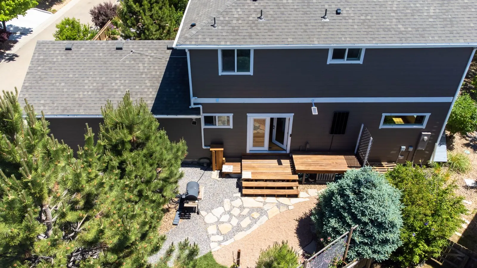 Backyard patio and garden behind a gray house from above