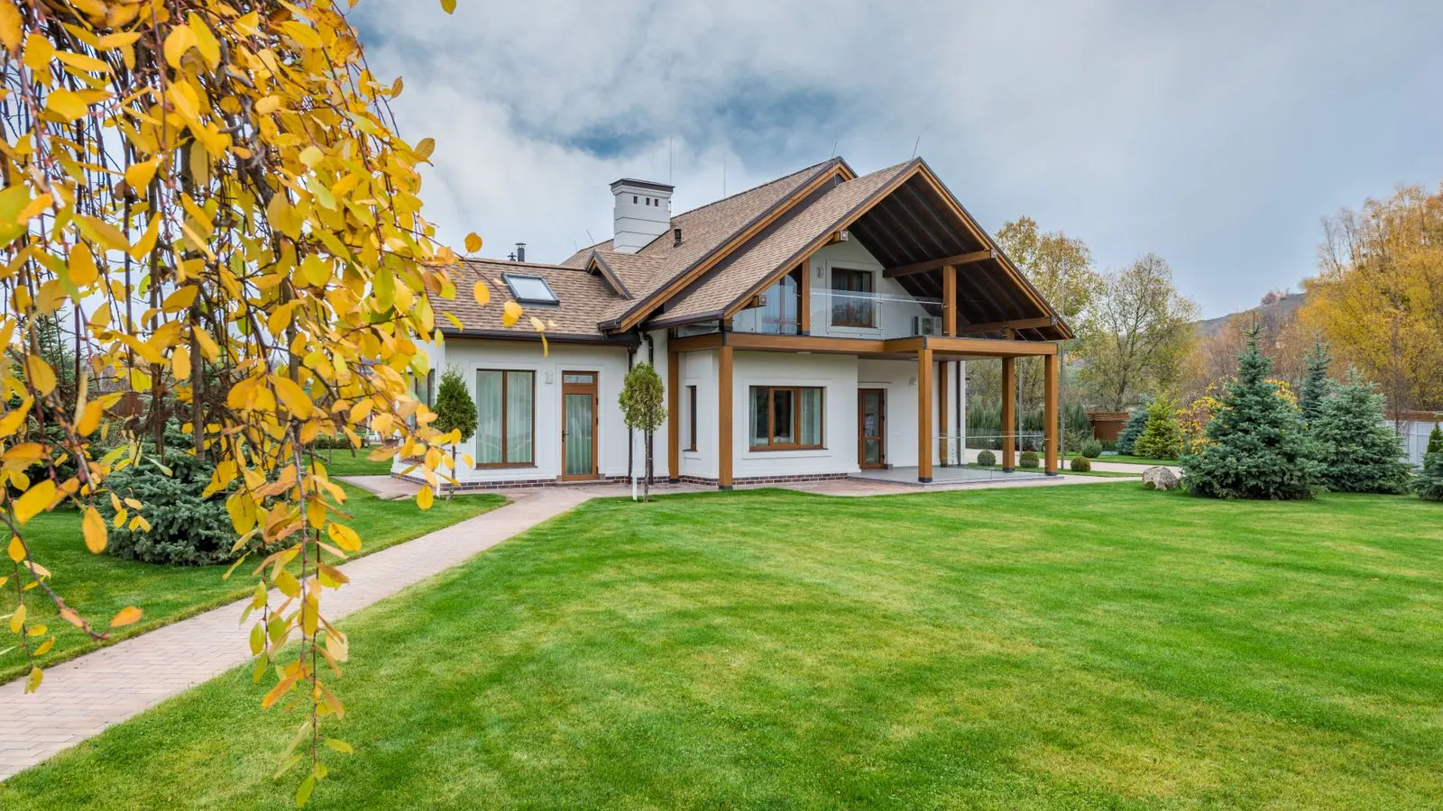 House with a big lawn and a tree turning yellow