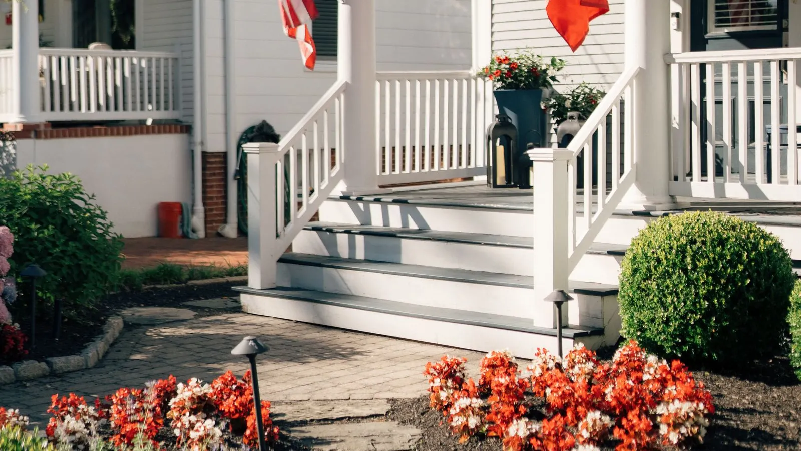 White porch hung with flags beside a garden